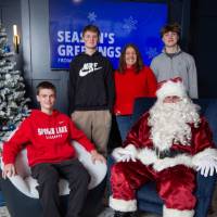 Mom with three boys smiles with Santa